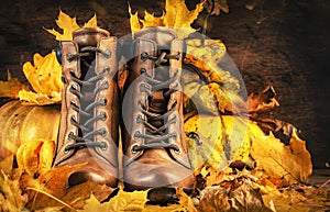 Autumn background with brown leather boots, pumpkins, maple and oak leaves on rustic wood background,. Country style female