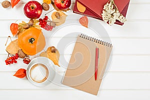 Autumn background, cup of cappuccino, notebook with red pen.