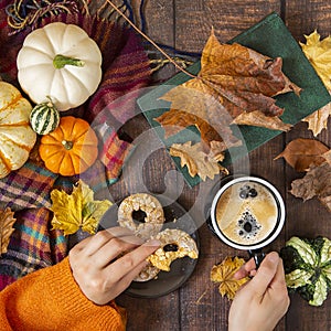 Autumn background. Decorative pumpkins, foliage hands and coffee with cookies on wooden background.top view.