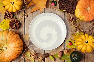 Autumn background with plate, fall leaves and pumpkin over wooden table.