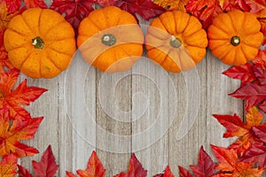 Autumn background with pumpkins and fall leaves on weathered woo