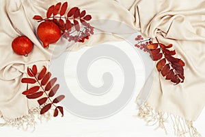Autumn background with rowan leaves red color and rowanberries on soft autumnal woman clothing scarf, orange pampkins on