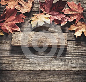 Autumn background with signboard, orange leaf on old grunge wood deck, copy place for inscription, Top view, tablet for text