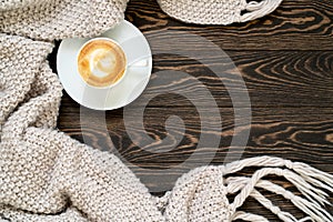 Autumn background. Top view of a cup of coffee and knitted plaid on the wooden table. Cozy and warm flat lay with copy space.