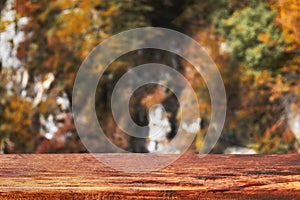 Autumn bokeh background with wooden plank in focus. Blurred fall nature with brown table