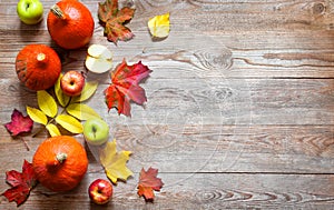 Autumn border from apples, pumpkin and fallen leaves on old wooden table