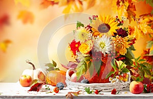 Autumn bouquet of beautiful flowers and berries in a pumpkin on wooden white table. Concept of autumn festive decoration for