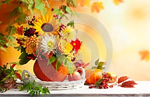 Autumn bouquet of beautiful flowers and berries in a pumpkin on wooden white table. Concept of autumn festive decoration for