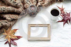 Autumn breakfast scene. Blank wooden picture frame mock-up with maple leaves, cup of coffee, scented candle and plaid. White