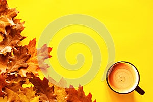 Autumn bright yellow background with yellow-brown autumn oak leaves and a cup of coffee