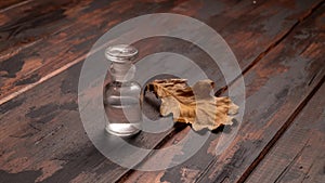 Autumn cinemagraph. Small bottle and oak leaf on wooden background.