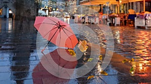 Autumn city street rain drops on  cafe table yellow leaves pink umbrella  on pavement in Tallinn old town