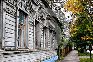 Autumn cityscape in a small Russian town, an old wooden house on a background of autumn leaves