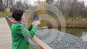 Autumn cloudy day Woman makes photo of a pond in a park The view from the back