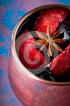 Autumn cocktail in copper mug with red plums