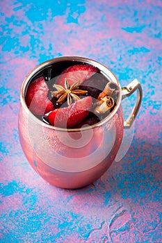 Autumn cocktail in copper mug with red plums