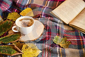 Autumn coffee cup with cozy blanket, fall deco warm home weekend with coffee cup, a book and dried leaves