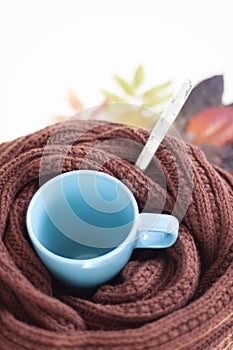 Autumn cold, illnes. Blue mug, knitted scarf, thermometer and autumn leaves.