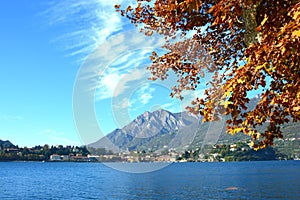 Autumn colorful foliage in red and yellow color over lake with beautiful mountain landscape on Lake Como, Italy