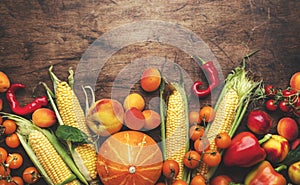 Autumn colorful vegetables and fruits set, apricots, tomatoes, pumpkin, peach, corn, etc. on rustic wooden background, top view,