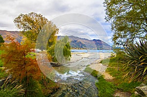Autumn colours at Lake Wanaka in Central Otago region of New Zealand, river stream, lake and hills at the background