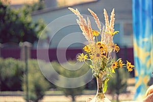 Autumn composition of a bouquet of yellow flowers in combination with dry grass