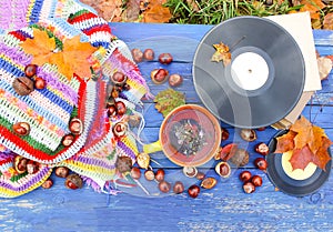 Autumn composition of ceramic cup of herbal tea and vintage vinyl records on aged wooden background with bright handmade crocheted