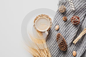 Autumn composition. Cozy home desk table with knitted sweater coffee mug, wheat, pine cones, decor on white background. Flat lay,