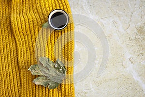 Autumn composition. Cup of coffee, blanket, autumn leaves, orange scarf on marble background. Flat lay, top view.