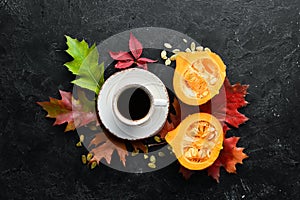 Autumn composition: A cup of coffee and colored autumn leaves. flat lay. On a black stone background.