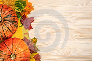 Autumn composition of fallen leaves of maple and pumpkins on wooden table, thanksgiving holiday party background