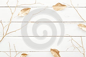 Autumn composition. Frame made of fall leaves and golden decorations on wooden white background. Flat lay, top view, overhead.