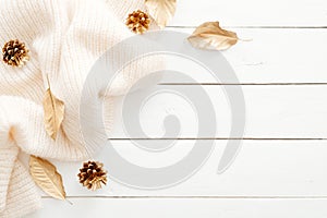 Autumn composition. Frame made of fall leaves, knitted scarf, golden decorations on wooden white background. Flat lay, top view,