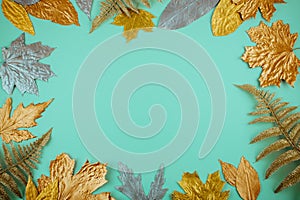 Autumn composition with golden leaves frame on blue mint background. Fall mockup with gold maple leaves. Flat lay, top view, copy