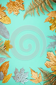 Autumn composition with golden leaves frame on blue mint background. Fall mockup with gold maple leaves. Flat lay, top view, copy