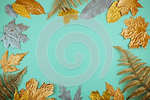 Autumn composition with golden leaves frame on blue mint background. Fall mockup with gold maple leaves. Flat lay, top view, copy