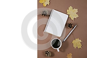 Autumn composition. Golden maple leaves, coffee cup, bumps, notebook and pen on brown background. Autumn or Winter concept.