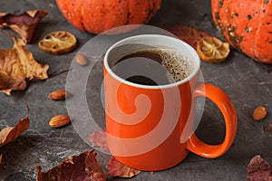 Autumn composition of mug of coffee, pumpkins, maple leaves, almond on dark stone table. Fall time