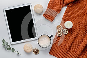 Autumn composition. Orange sweater and digital tablet with a cup of cocoa on a white table. Lifestyle, still life