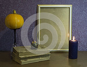 Autumn composition. A photoframe, books, a pumpkin and a candle on a beautiful background. Autumn, Halloween concept.