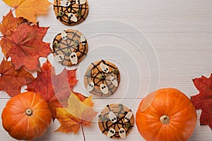 Autumn composition from pumpkins, maple leaves, Halloween Cookies with ghosts, spiderweb on a white wooden background. Concept of