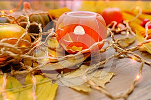 Autumn composition on rustic wooden table in garden with pumpkin, fallen yellow, orange leaves and berries, concept happy