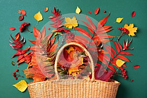 Autumn composition. Straw bag with autumn dried leaves on green background. Flat lay. Top view. Copy space. Fall season