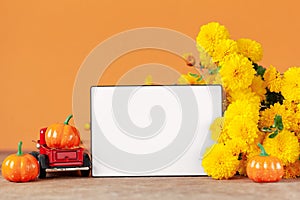 Autumn composition with Yellow chrysanthemums flowers and empty blank lightbox on orange background