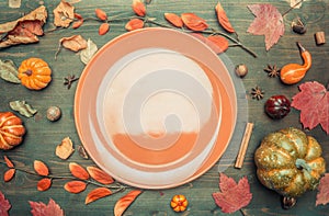 Autumn composition, yellow leaves, small pumpkins lined around brown plate, space for text flat lay