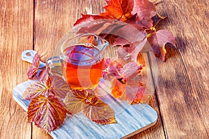 Autumn concept drink warm morning tea, healthy natural infusion of raspberry leaves for herbal therapy on a wooden background.