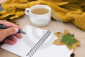 Autumn concept. Hand writes in a blank notebook