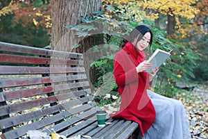 Young asian sensual woman reading a book sit bench in romantic autumn scenery.Portrait of pretty young girl in autumnal forest