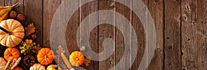 Autumn corner border banner of pumpkins, gourds and fall decor on a rustic wood background