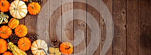 Autumn corner border of pumpkins, gourds and pine cones on a rustic dark wood banner background